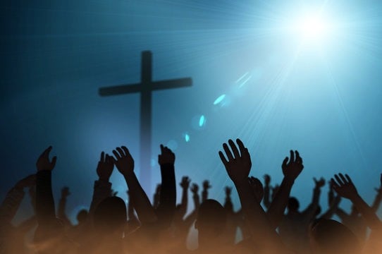 Raised hands in worship beneath a cross